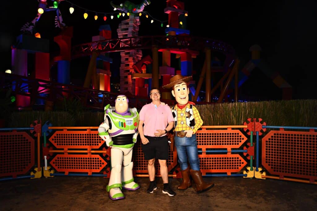 Daniel posing with Buzz Lightyear and Woody in Toy Story Land at Walt Disney World at night